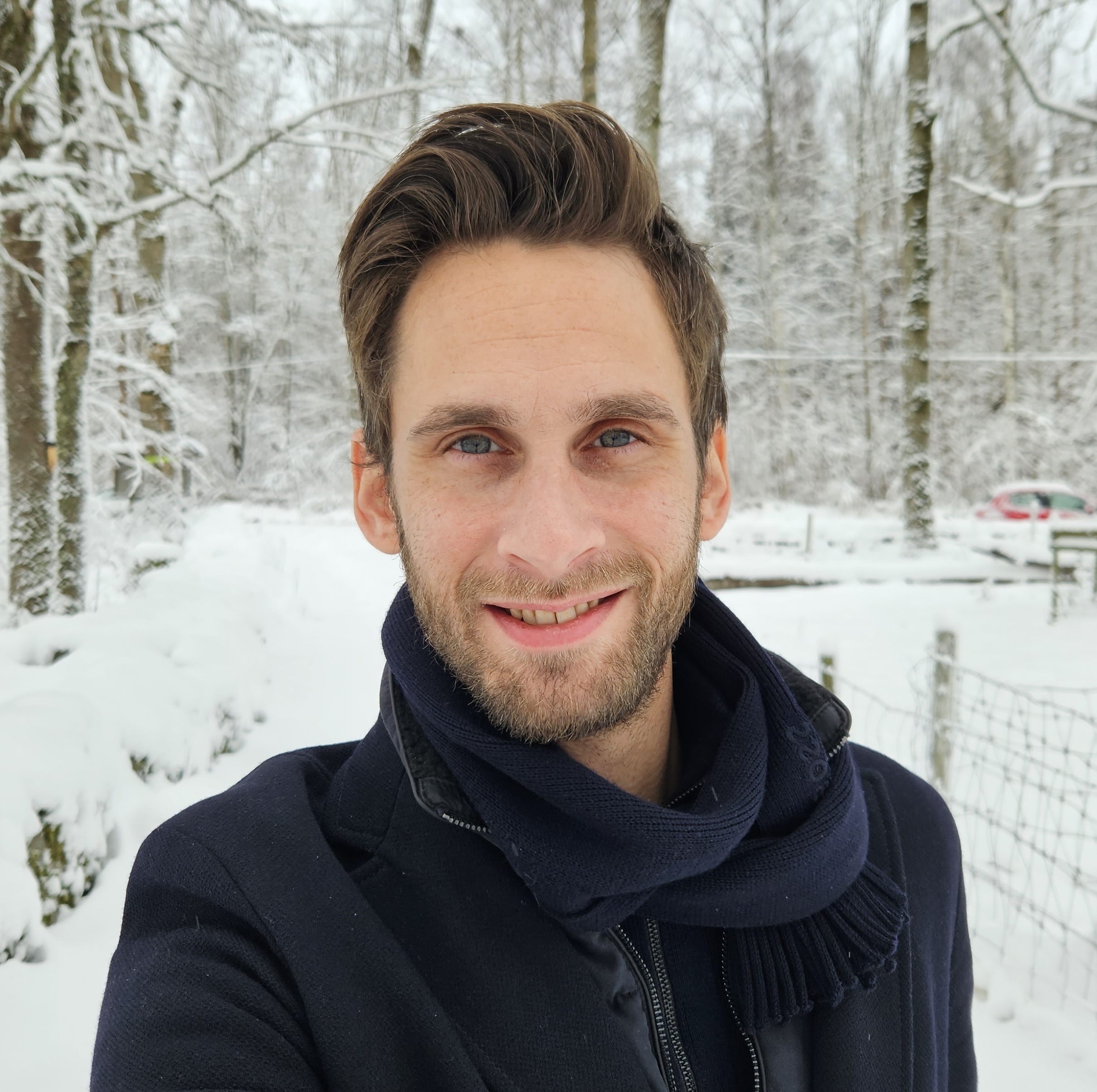 Robin Kamstedt smiling outdoors in a snowy winter forest
